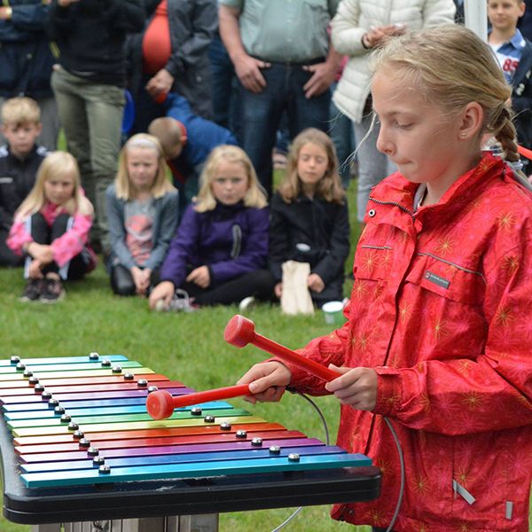school girl playing colourful outdoor xylophone in a school playground
