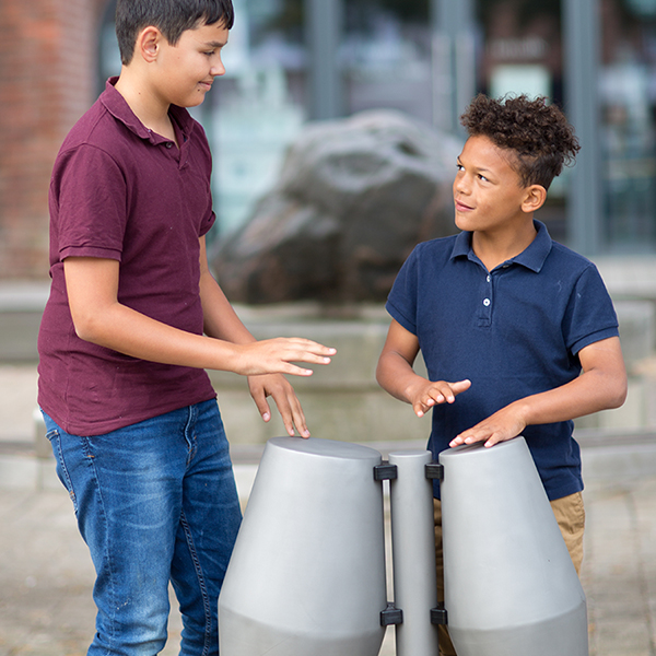 two young brothers are playing a pair of tumbardora steel drums with their hands in the street