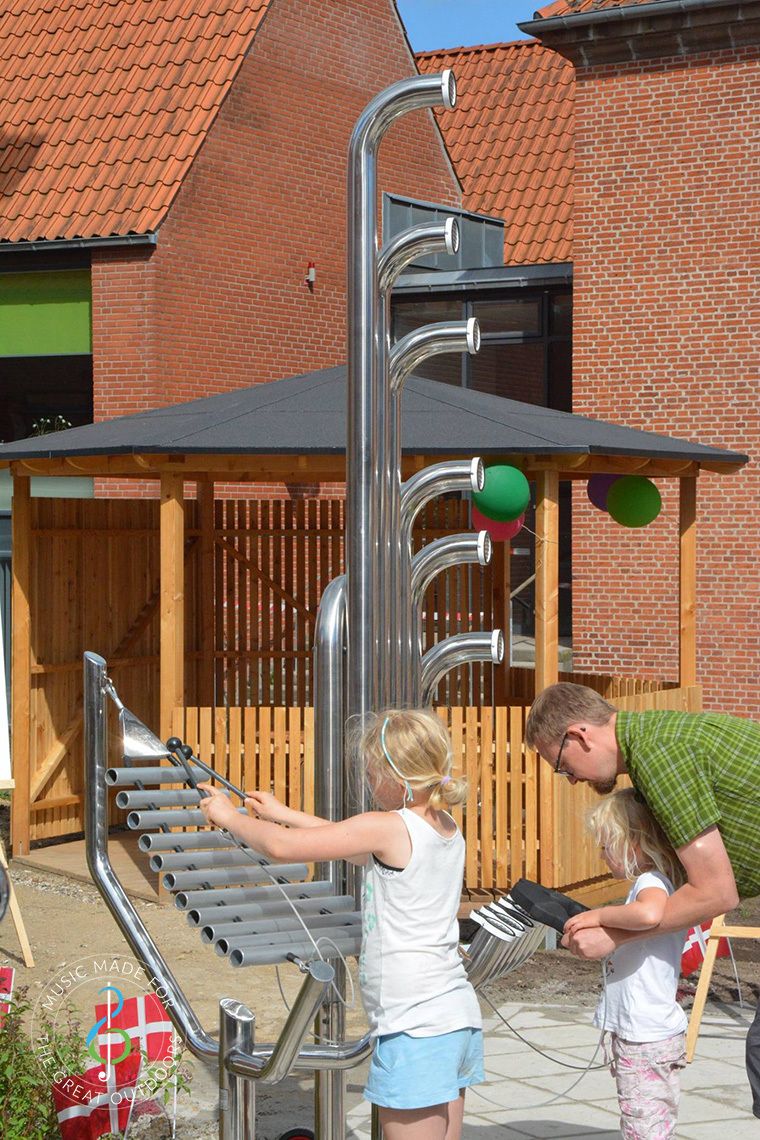 father and two daughters playing large outdoor musical instruments in playground
