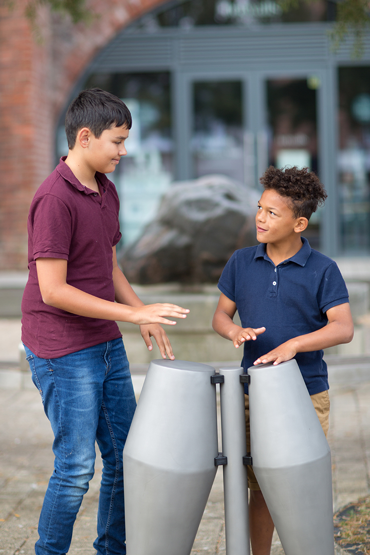 two brothers playing on a pair of outdoor Tumbadora drums in a street