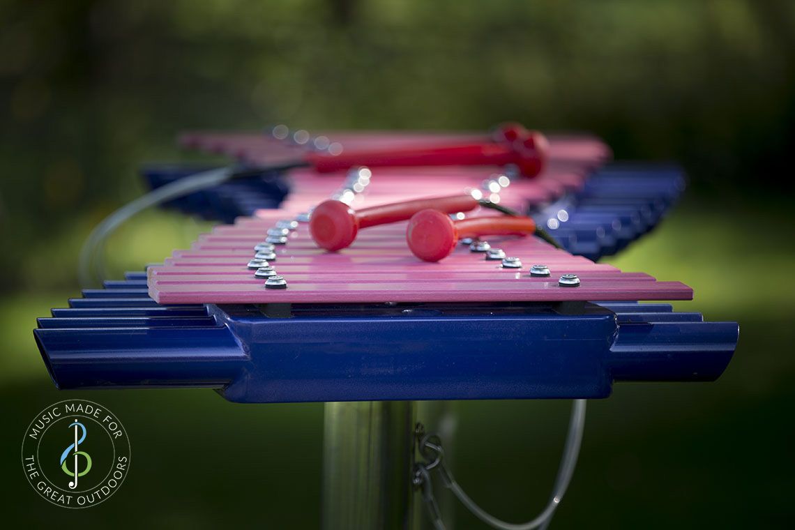Close up image of large outdoor xylophone with pink grp notes and indigo blue abs resonators 