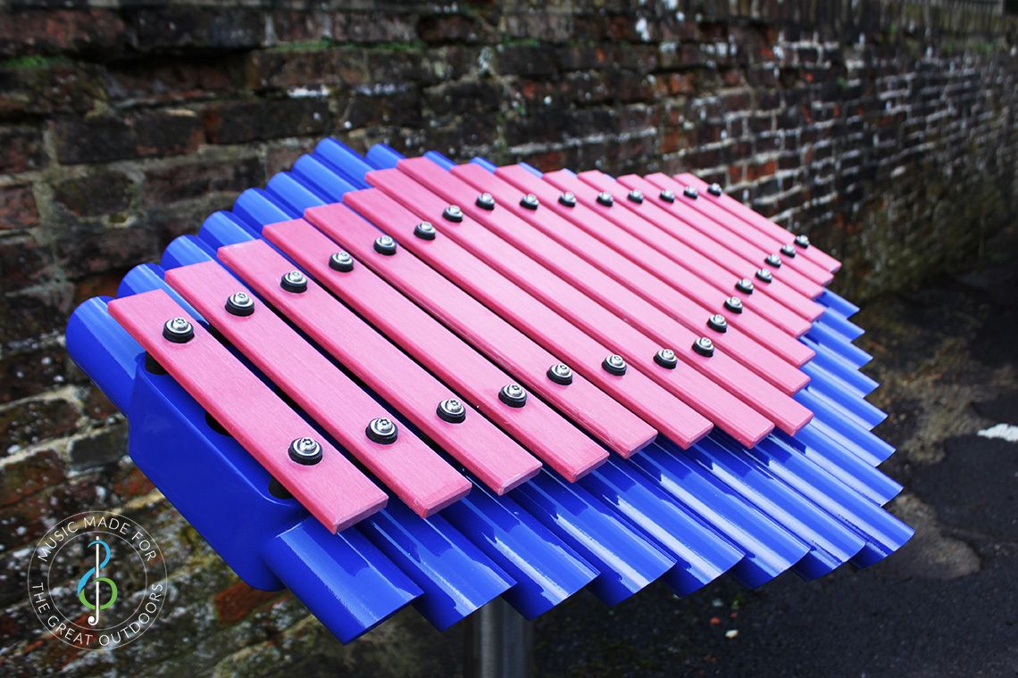 close up of outdoor xylophone with pink notes and blue resonators