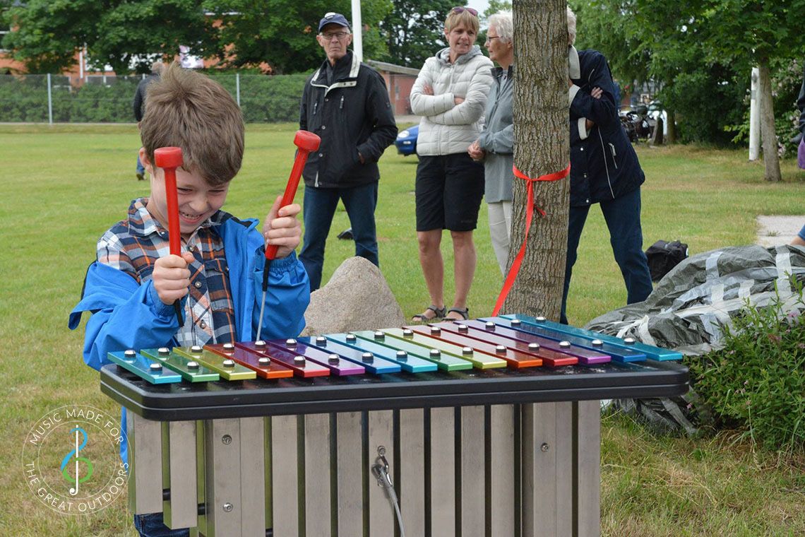 Boy Playing Rainbow Coloured Outdoor Xylophone in Park