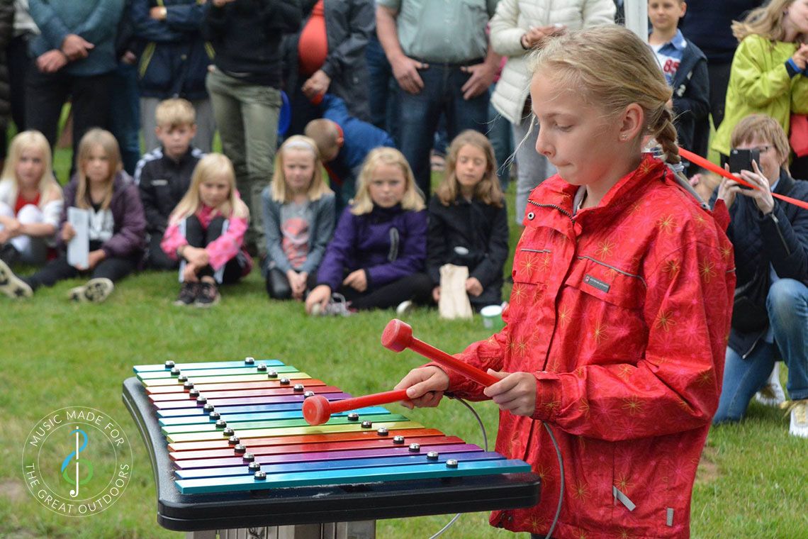 Girl Playing Rainbow Coloured Outdoor Xylophone with Audience