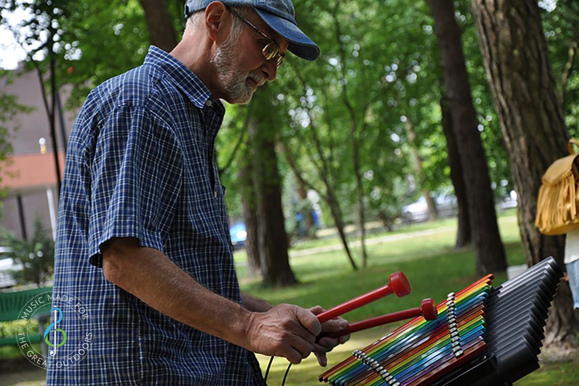 Older Man Playing Colourful Outdoor Xylophone in Park 