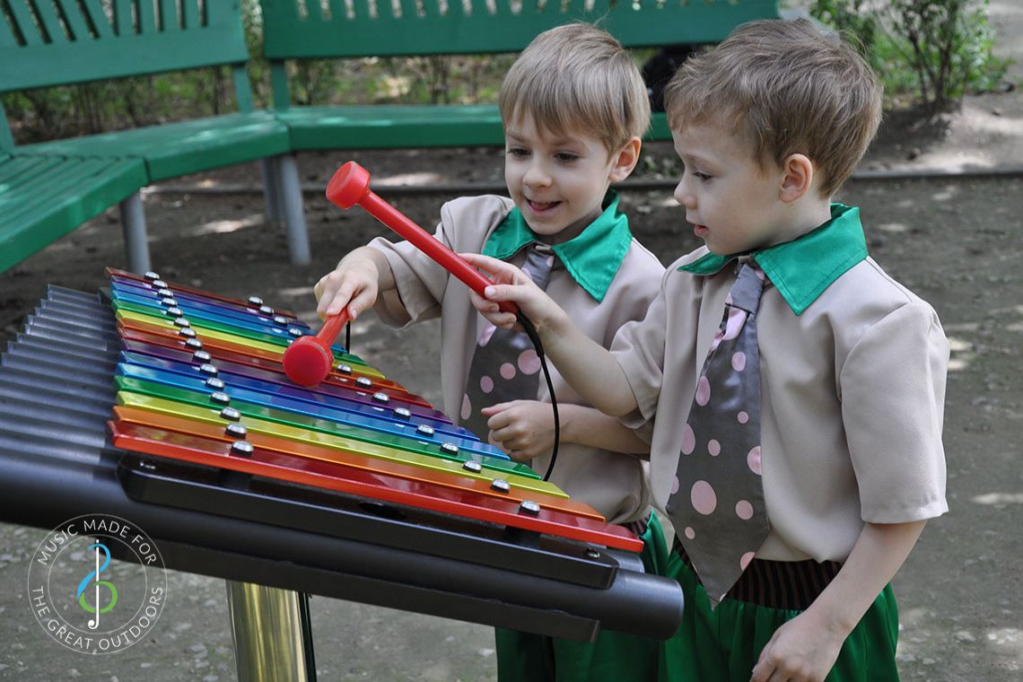 Two Young boys in Funny Ties Playing Rainbow Coloured Xylophone in Playground