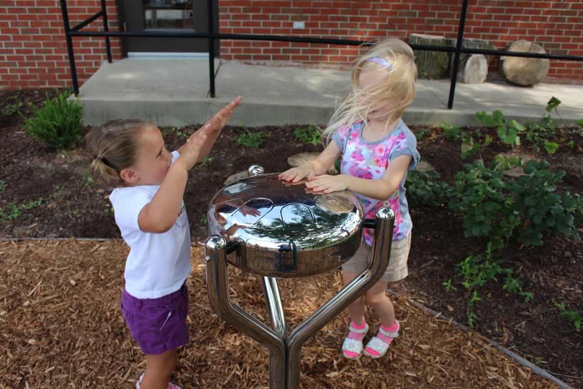 two little girls Playing Stainless Steel drum in playground